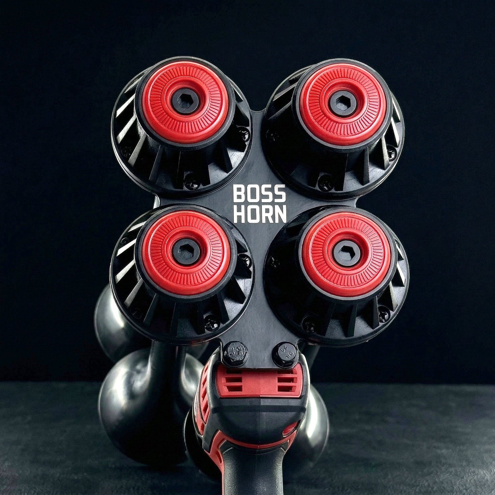 Front view of the four red-and-black trumpet horns with curved bells below, mounted on the unit against a dark gray background - view 5